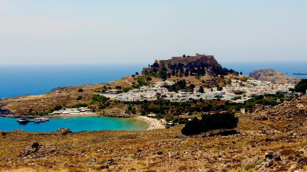 Lindos Griekenland_bruine-en-groene-bergen-bekken-blauwe-zee-onder-blauwe-hemel-tijdens-de-dag